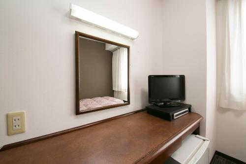 a room with a television and a mirror on a counter at Nawa Plaza Hotel in Tokai