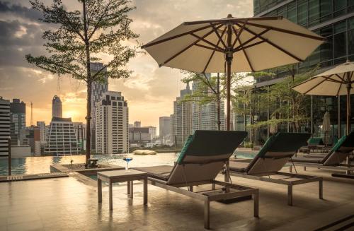 two lounge chairs and an umbrella on a building at Sivatel Bangkok Hotel in Bangkok