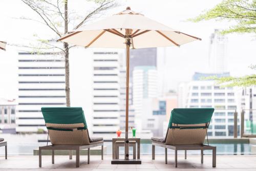 two chairs and an umbrella on a patio at Sivatel Bangkok Hotel in Bangkok