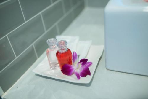 a bottle of vinegar and a purple flower on a plate at Coconut Grove Hotel Samui in Chaweng
