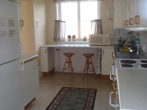 a kitchen with a refrigerator and two bar stools at Gustafsbergs Badhotell & Vandrarhem in Uddevalla
