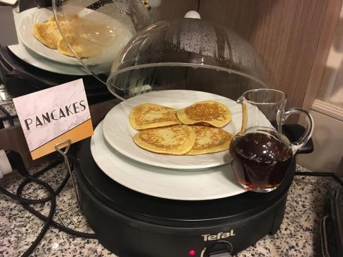a plate of pancakes and a glass of red wine at Mercure Perpignan Centre in Perpignan