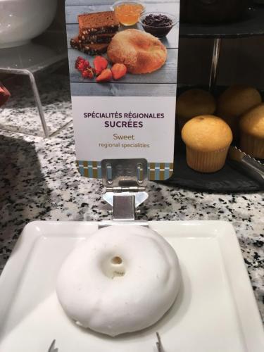 a doughnut sitting on a white plate on a counter at Mercure Perpignan Centre in Perpignan