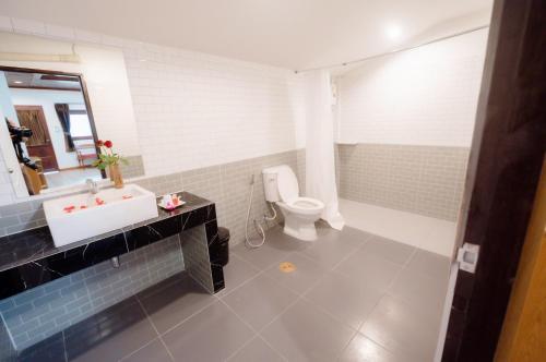 a bathroom with a white sink and a toilet at Coconut Grove Hotel Samui in Chaweng