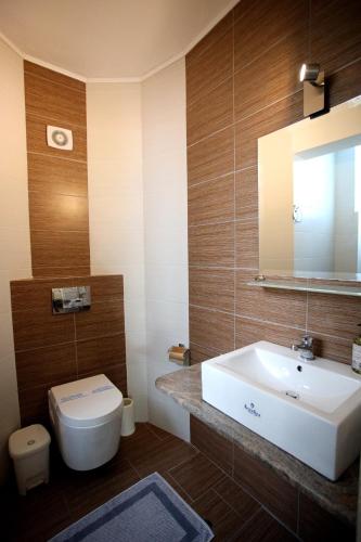 a bathroom with a sink and a toilet and a mirror at Paris Village Apartments in Chrani