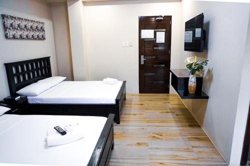 a hotel room with two beds and a television at The Mang-Yan Grand Hotel powered by Cocotel in Puerto Galera
