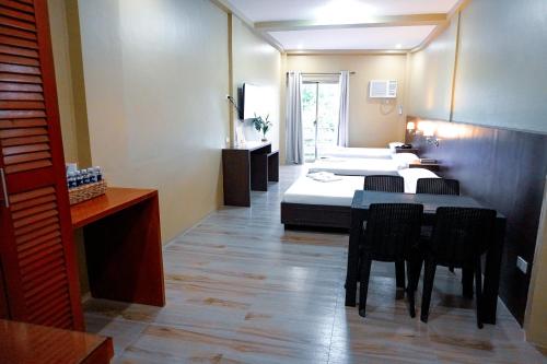 a room with a bed and a table and chairs at The Mang-Yan Grand Hotel powered by Cocotel in Puerto Galera