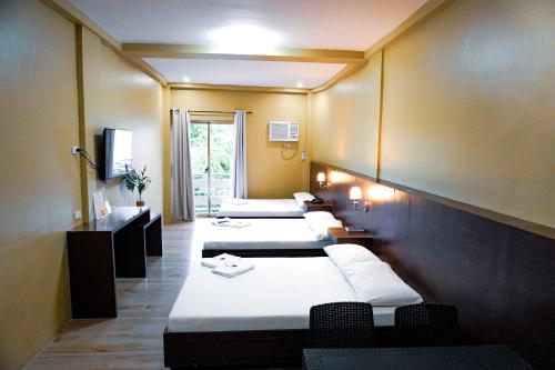 eine Reihe von Betten in einem Hotelzimmer in der Unterkunft The Mang-Yan Grand Hotel powered by Cocotel in Puerto Galera