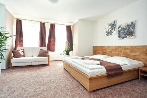 a bedroom with a large bed and a white couch at Vila Encore in Valašské Meziříčí