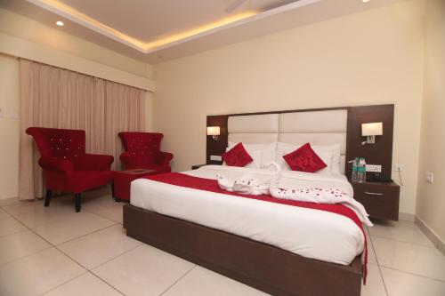 a bedroom with a large bed and two red chairs at Indira Nikunj Rubystone Exotic in Rishīkesh