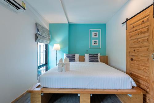 1 dormitorio con cama y pared azul en Pakta Phuket - SHA PLUS, en Phuket