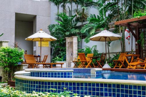 een zwembad met stoelen, tafels en parasols bij Silom Serene A Boutique Hotel - SHA Extra Plus in Bangkok