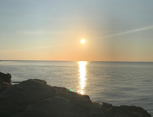 a sun setting over the ocean with rocks in the foreground at On the Rocks in Koh Rong Sanloem