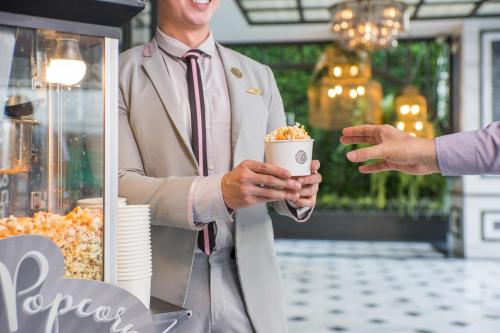 a man in a suit and tie holding a cup of popcorn at The Salil Hotel Sukhumvit 57 - Thonglor in Bangkok