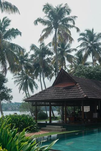 a pavilion next to a swimming pool with palm trees at Vismaya by Moksha Stays in Turavūr