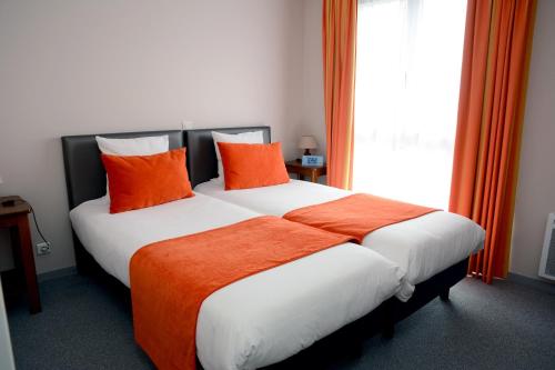 a bedroom with a bed with orange pillows and a window at Hôtel Restaurant La Paix La Robe et le Palais in Forges-les-Eaux