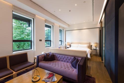 um quarto de hotel com uma cama e um sofá roxo em Diaoyutai Boutique Hotel Chengdu em Chengdu