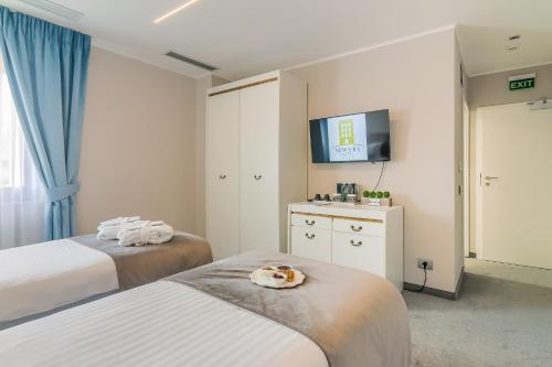 a hotel room with two beds and a flat screen tv at New Era Hotel Old Town Bucharest- parking with fee nearby - NOT at the hotel ! in Bucharest