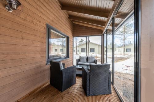 eine abgeschirmte Veranda mit Stühlen, einem Tisch und Fenstern in der Unterkunft Holiday Club Kuusamon Tropiikki in Kuusamo