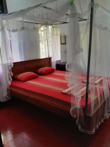 1 dormitorio con cama con dosel y almohadas rojas en Dreams Garden Surf Lodge, en Midigama East