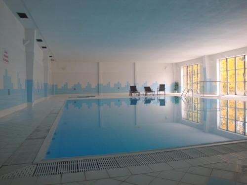 a large swimming pool with two chairs in a building at Hotel Astra in Tuchlovice