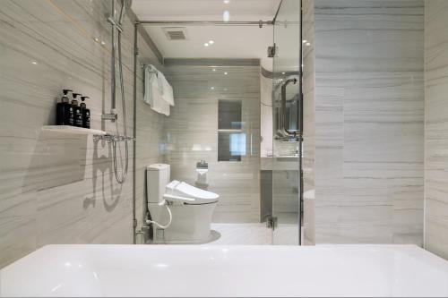 a bathroom with a toilet and a glass shower at The Salil Hotel Sukhumvit 57 - Thonglor in Bangkok