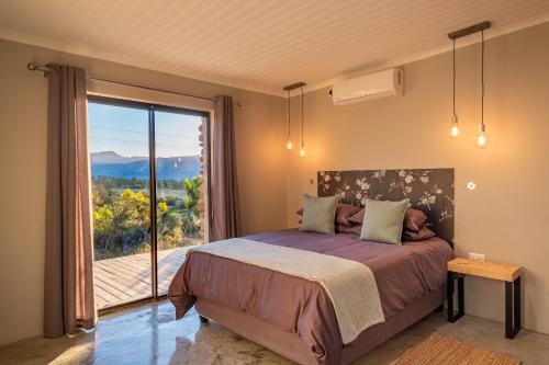 a bedroom with a bed and a balcony with a view at Steenbok farm cottages Aalwyn Cottage in Wolseley