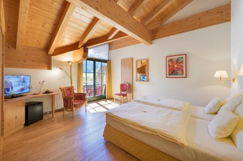 a bedroom with a large bed in a room with wooden ceilings at Golf- und Sporthotel Moarhof in Walchsee