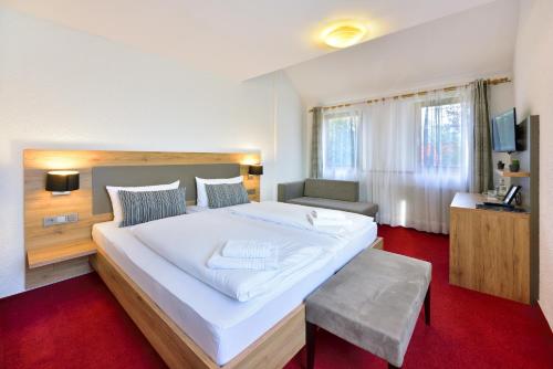 Vico's Hotel & Restaurant Asperg في Asperg: غرفة نوم بسرير ابيض كبير وسجادة حمراء