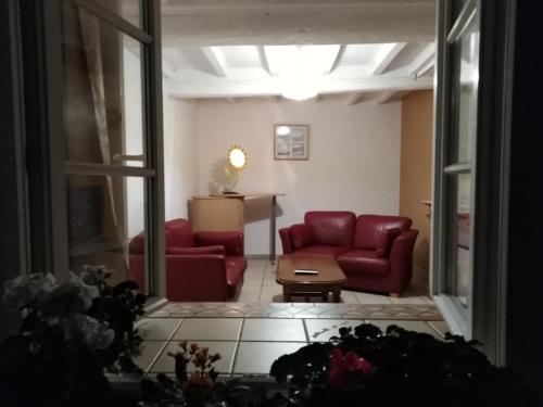una sala de estar con 2 sofás rojos y una mesa. en Gîtes Rose des Sables, en Surtainville