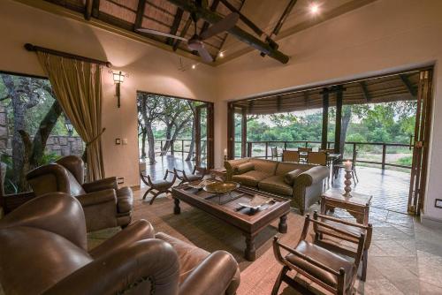 a living room with leather couches and a table at Shumbalala Game Lodge in Thornybush Game Reserve