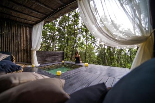 a woman sitting on the deck of a tent with a pool at Villa Experience - Relais Il Termine Elba in Rio Marina