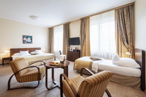 a hotel room with two beds and a table and chairs at Hotel Devín in Bratislava