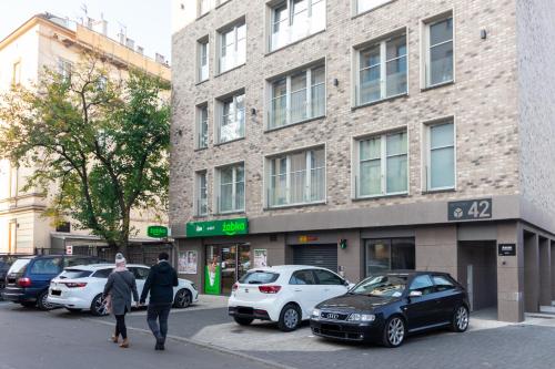 dwie osoby idące ulicą przed budynkiem w obiekcie Apartment NEARTO Old Town Miodowa Parking w Krakowie