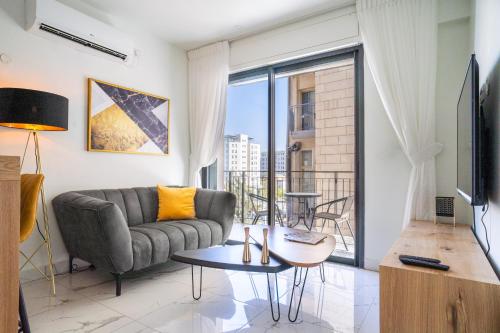 a living room with a couch and a large window at Eshel Suites Even Israel in Jerusalem