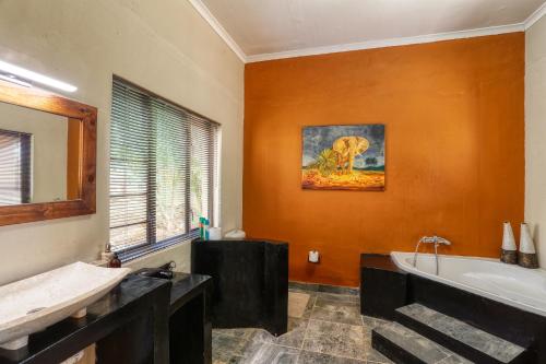 een badkamer met een bad en een schilderij van een olifant bij Ijaba Lodge at Buschfeld Park in Outjo