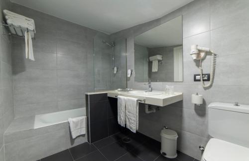 a bathroom with a sink and a tub and a mirror at Hotel La Palma de Llanes in Llanes