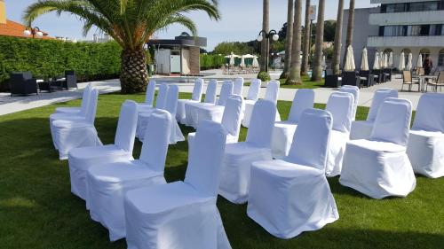 
a row of white chairs sitting in a grassy area at Hotel La Palma de Llanes in Llanes
