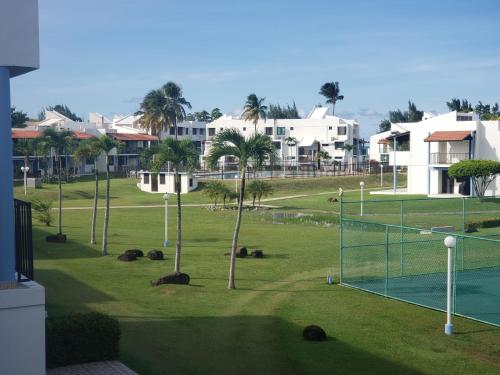 a tennis court in a park with palm trees and houses at Relax Beachfront Complex at Rio Grande in Rio Grande