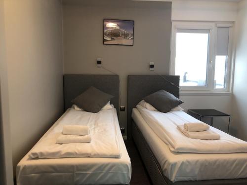 two beds in a small room with a window at Brygga Gjestehus in Harstad