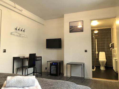 a bedroom with a bed and a desk and a toilet at Brygga Gjestehus in Harstad