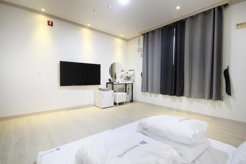a bedroom with a bed and a flat screen tv at Mj Hotel in Yeosu
