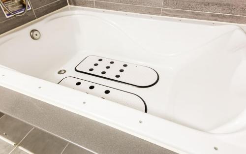 a white bath tub in a tiled room at Mj Hotel in Yeosu