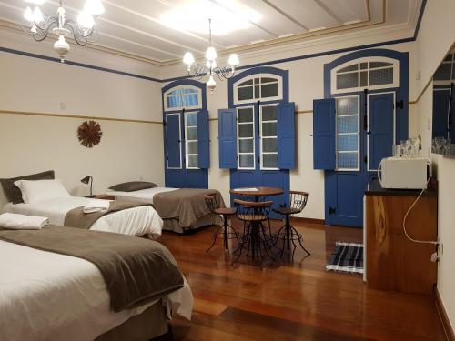 Habitación con 2 camas y ventanas con persianas azules. en Suíte Marília de Dirceu, en Ouro Preto