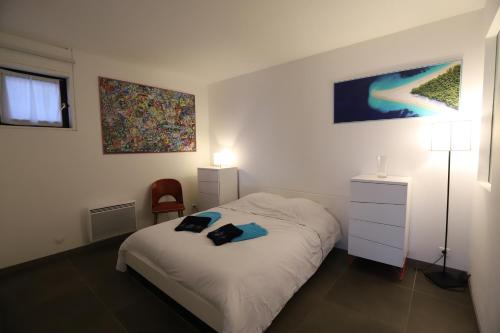um quarto com uma cama com um candeeiro e uma cadeira em Superbe appartement Vue Mer et Piscine em Bandol