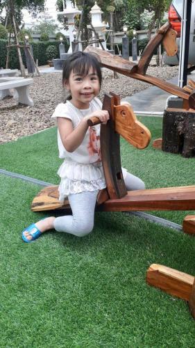 a little girl sitting on a park bench at Naiya Place in Kanchanaburi