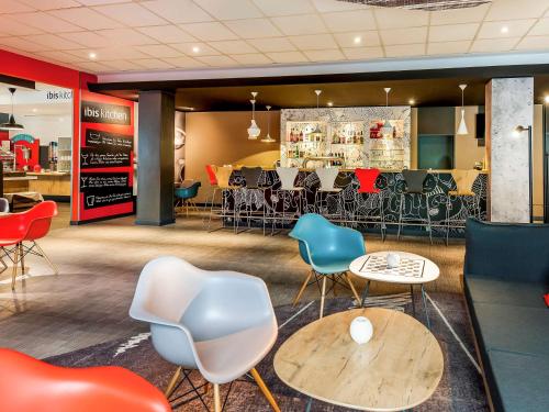 a restaurant with chairs and tables and a bar at ibis Hotel Frankfurt Airport in Kelsterbach