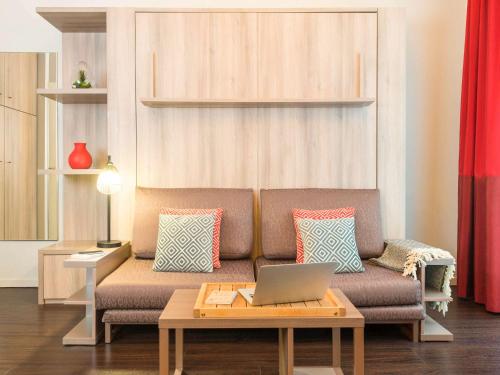 a living room with a couch with a laptop on it at Aparthotel Adagio Brussels Grand Place in Brussels