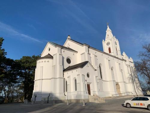 a white church with a tower and a car parked in front at Villa Pazelt Top1 in Bad Vöslau