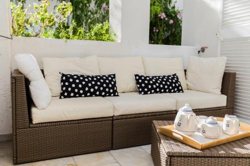 a wicker couch with black and white pillows on a patio at Oasis Club II Triplex Apartment by Rock Rentals in Jávea